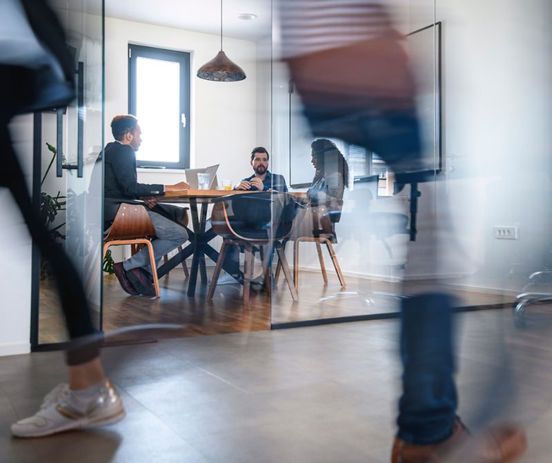 Workspace with table and three people having a discussion